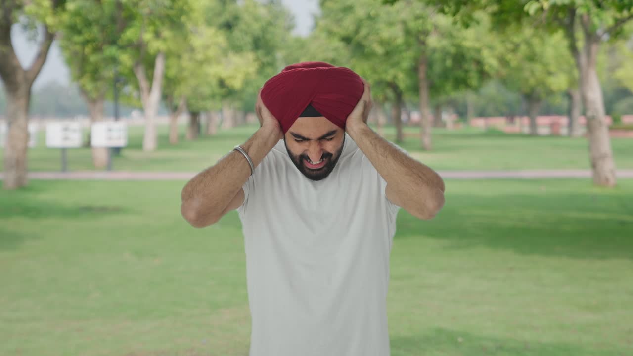 Pria Sikh India yang marah berteriak dengan telinga tertutup di taman.