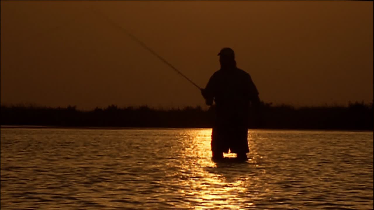 A Fly Fisherman Stands In A River At Sunset In This Beautiful Shot