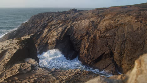 water shooting out from the rocks - blowhole in porth island, newquay, cornwall - wide shot