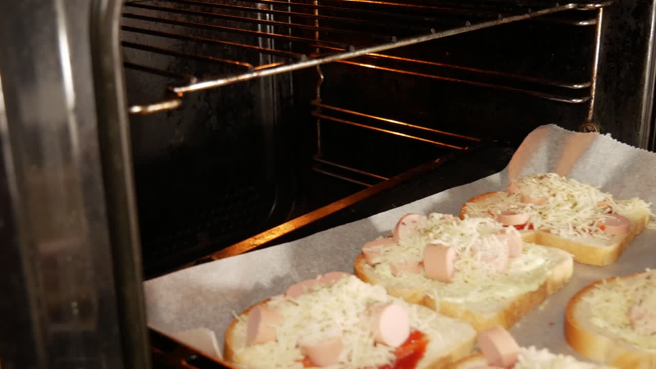 Hombre casado con anillo de boda metiendo sándwiches caseros en el horno caliente para cocinar.