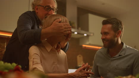 Family-making-surprise-for-grandmother-at-birthday.-Senior-woman-looking-at-cake