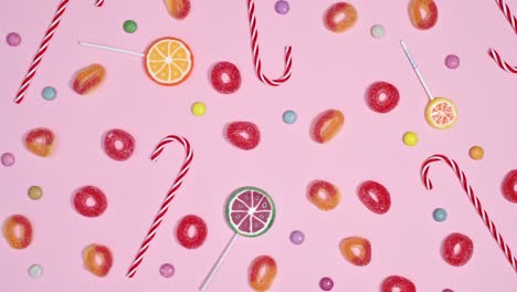 lollypops, candies and gummy candies filling pastel pink background and making pattern. stop motion animation flat lay