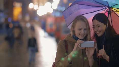 women making funny selfie in evening rainy city