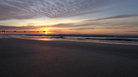 Waves-hitting-the-coast-of-Emerald-island,-the-Bogue-Inlet-Pier,-at-a-sunny-colorful-dawn-and-sunrise,-in-North-Carolina