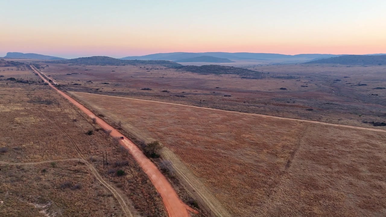 Veicolo utilitario 4x4 che guida su una strada sterrata polverosa del Sudafrica al tramonto. Vista aerea.