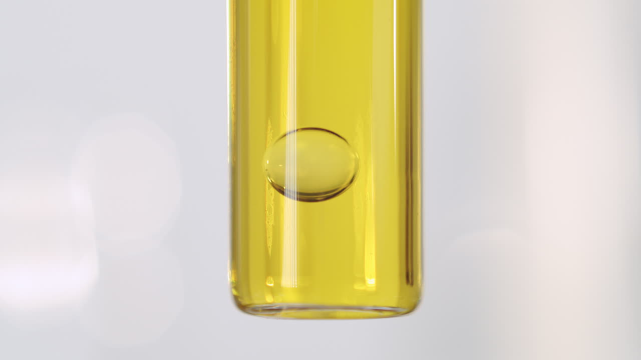 과학 유리 제품 내부의 노란색 액체에 기포가 떨어지고 보기를 닫습니다.