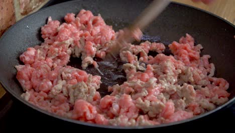 spaghetti, close-up of frying ground meat on a pan, which is being stirred with a wooden spoo