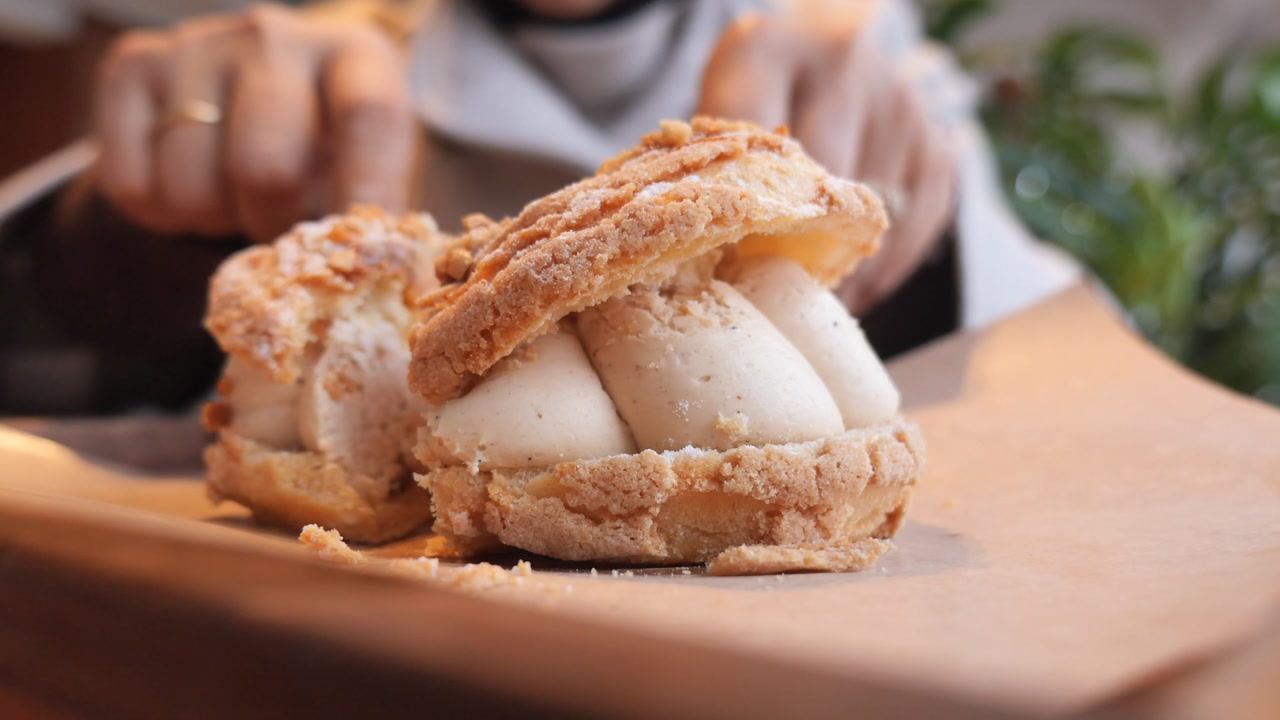 Close-up of a Person Cutting a Cream-Filled Choux Pastry Dessert