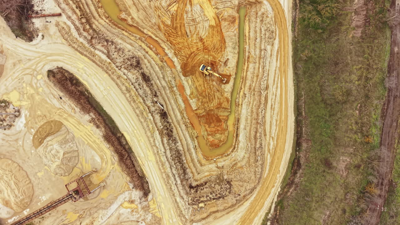 Schwere Maschinen bewegen die Erde, um die Landschaft auf einer Baustelle in der Nähe eines Flusses tagsüber umzugestalten, wodurch rote und braune Farbtöne im Boden sichtbar werden