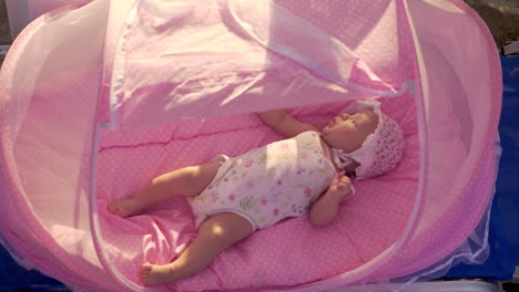 baby in pink bassinet at the beach