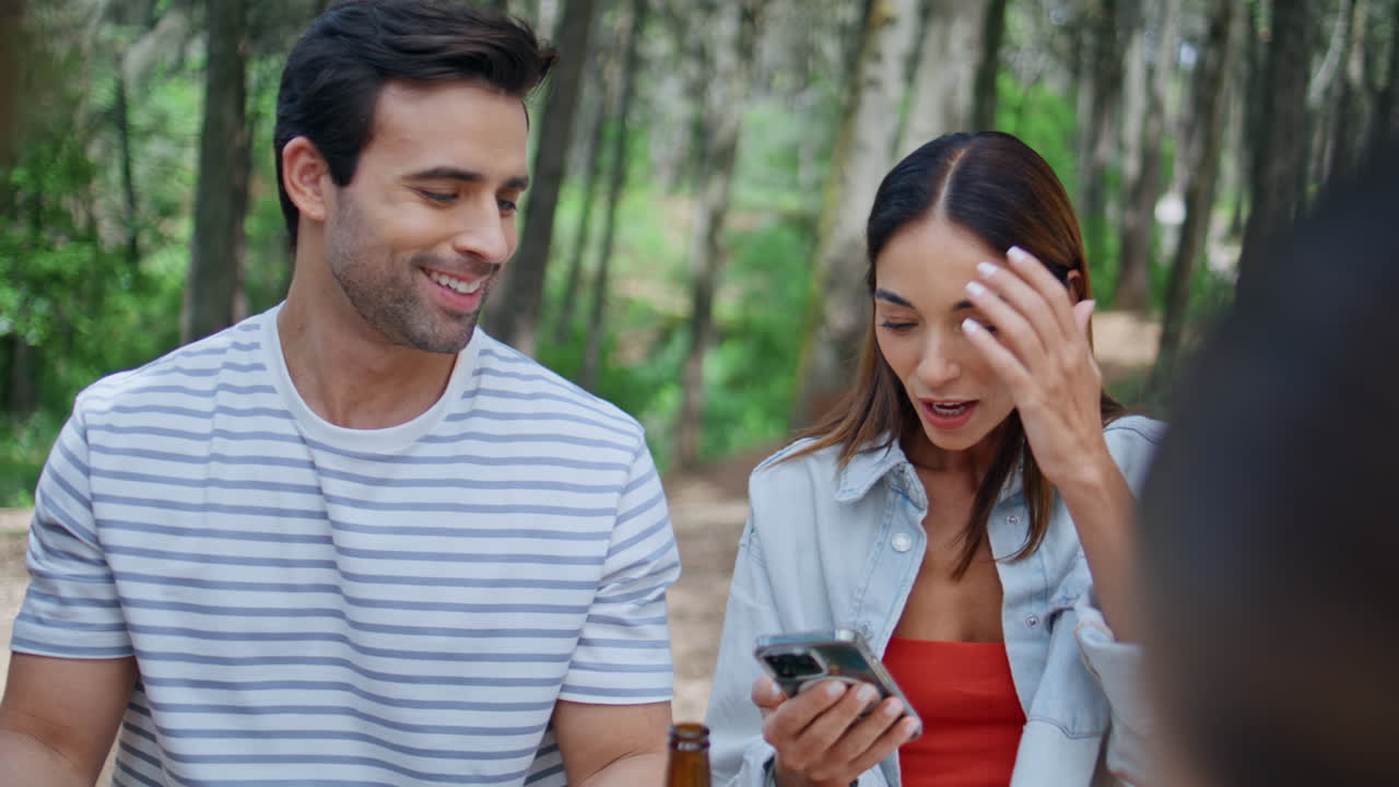 Carefree people discussing smartphone content sitting park at picnic closeup