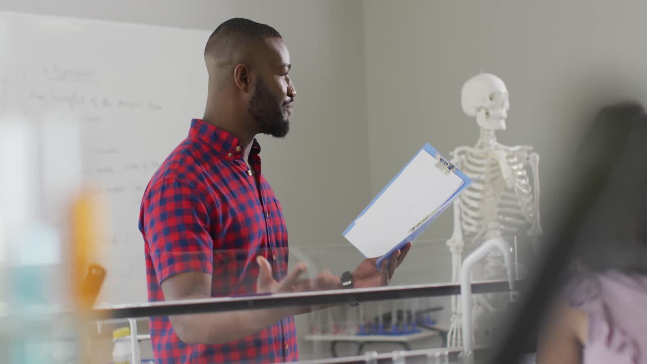 video de un feliz maestro afroamericano con una clase de alumnos diversos durante la lección de anatomía