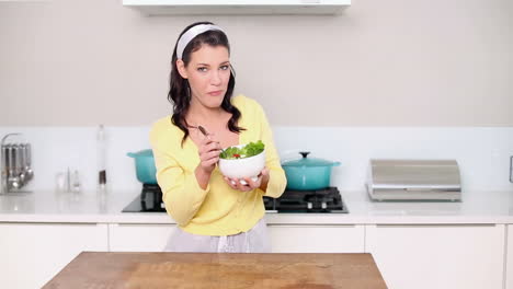 una hermosa morena comiendo un plato de ensalada