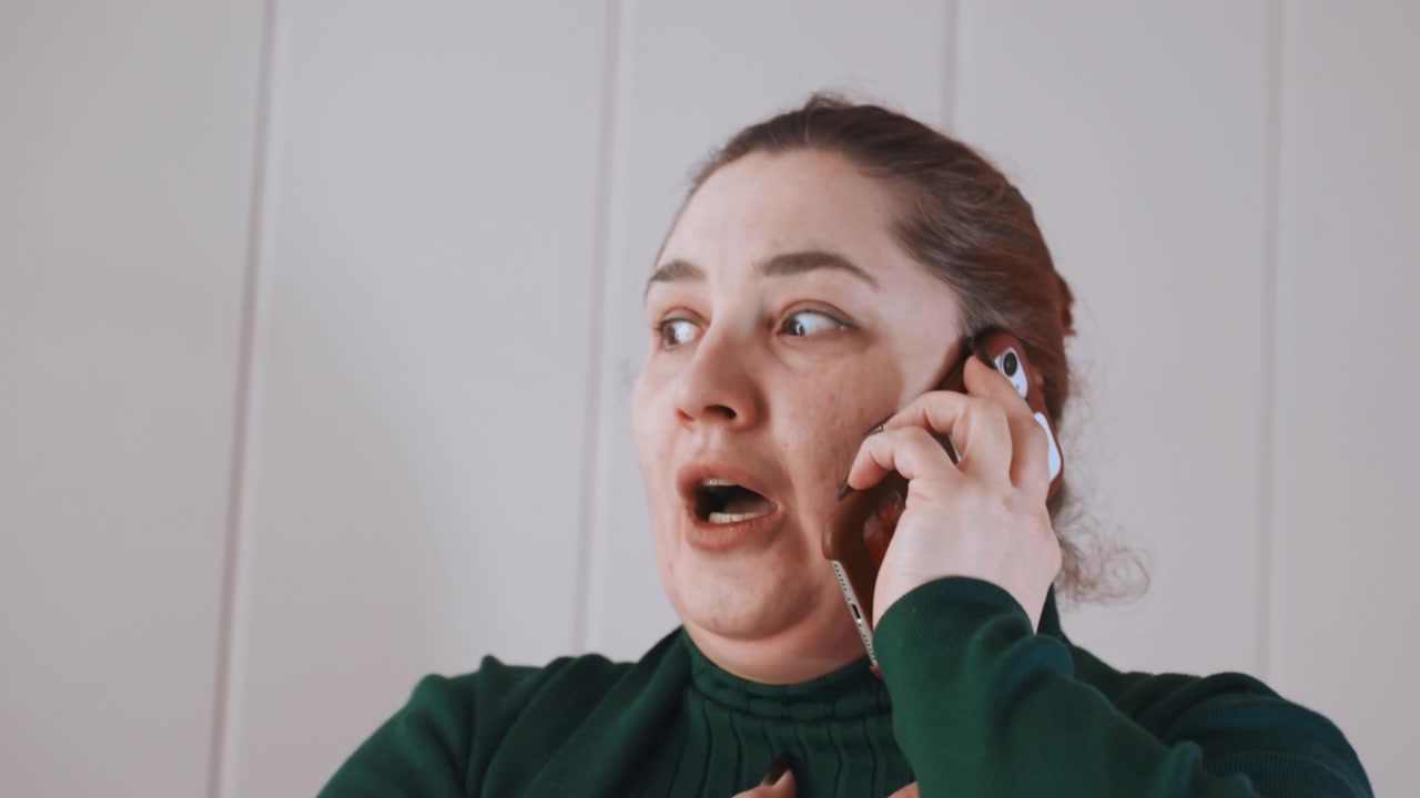 Una donna implora disperatamente. Una donna chiede aiuto con urgenza. Una donna frenetica al telefono cerca assistenza immediatamente. Una donna ansiosa si preme una mano al petto mentre parla con urgenza.
