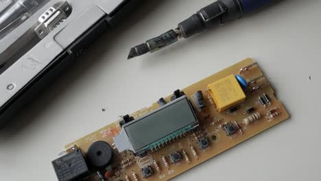 close-up of an electronic circuit board with components and soldering tools