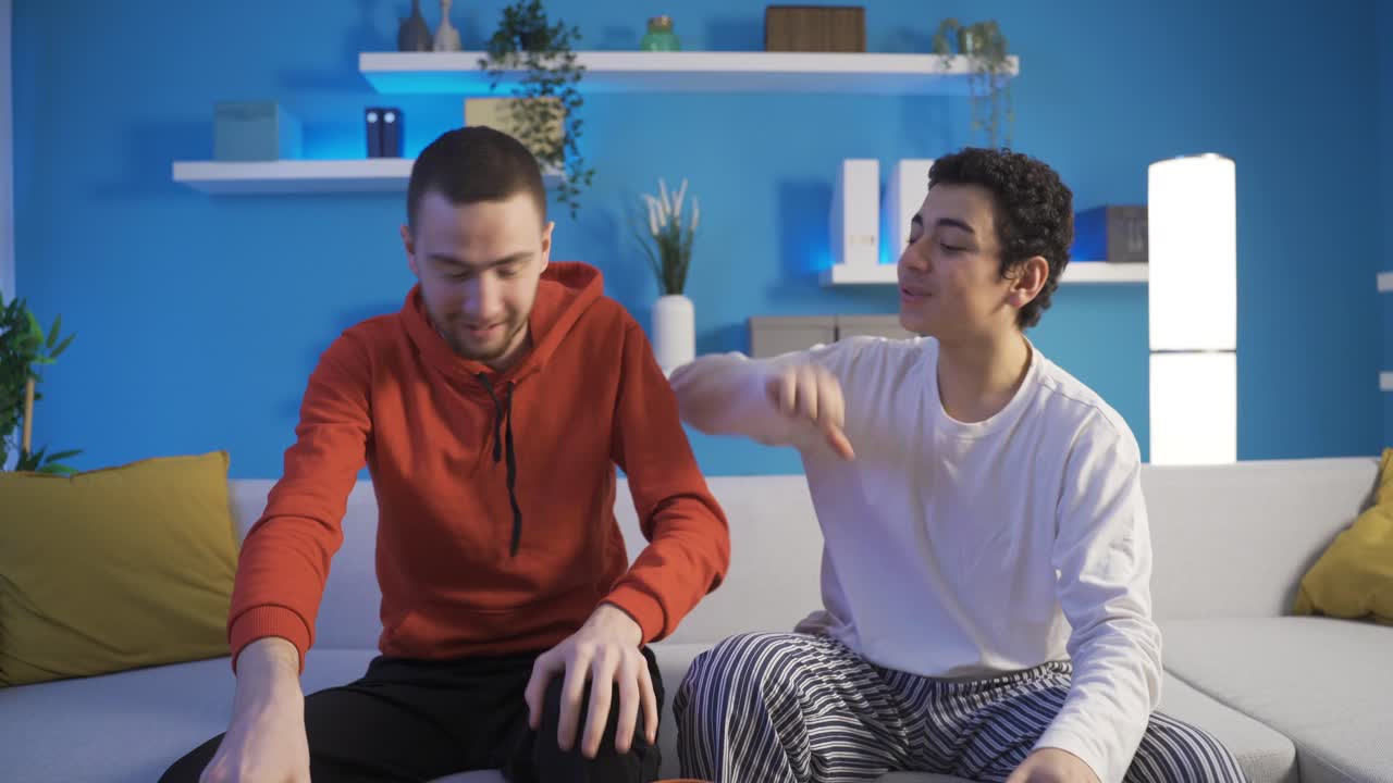 젊은 남자가 동생과 함께 게임 콘솔을 사용하여 비디오 게임을하고 있습니다.