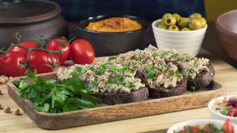 israeli cuisine. hands putting forshmak with black rye bread decorated with parsley close-up. national jewish herring dish, middle eastern culture. traditional snack vorschmack made of fish fillet