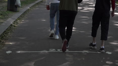 people walk and cycle past pavement markings in a park that show two metre social distancing during the coronavirus outbreak