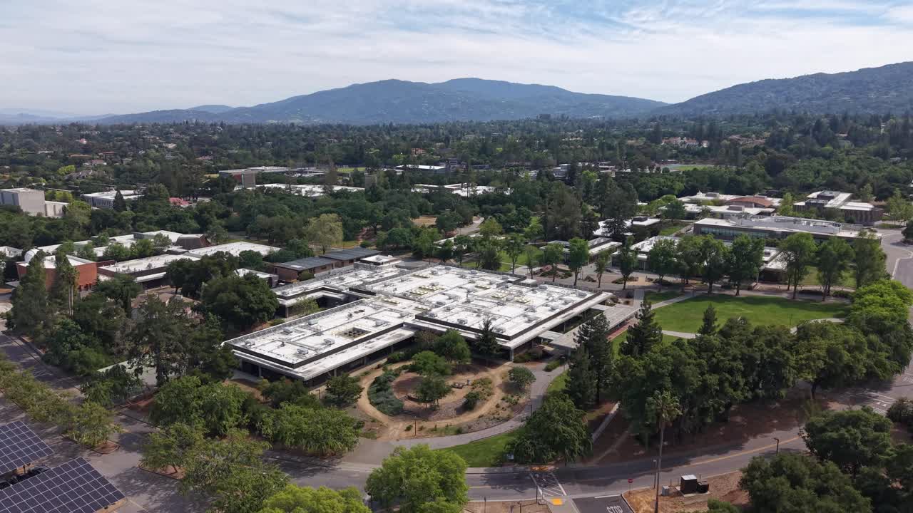 Luftfoto fra høj vinkel af den frodige West Valley College campus, beliggende i byen Saratoga, Californien, med Santa Cruz-bjergene synlige i den naturskønne baggrund.