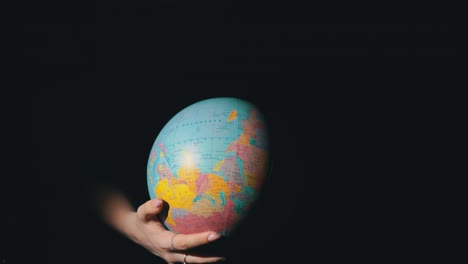 girl's hands twist the geographic globe around its axis