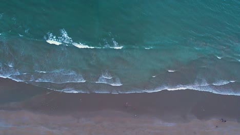 Vista-Aérea-De-Suaves-Olas-Golpeando-Una-Playa-De-Arena-Desde-La-Vista-Superior