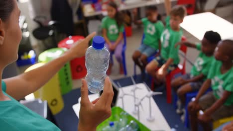 maestra caucásica que enseña a los escolares sobre el reciclaje de botellas en el aula 4k