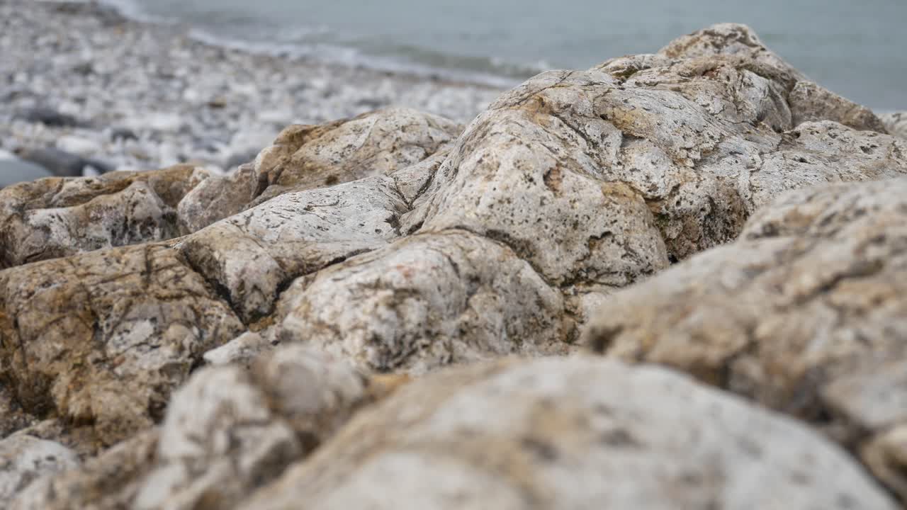 costa de piedra de guijarros rocosos con olas del océano fondo paisaje marino primer plano derecho dolly