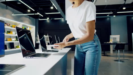 woman examining laptops in an electronics store