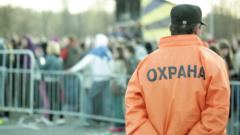 back of a security guard in front of blurred crowd