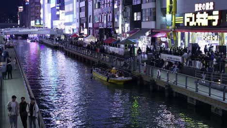 boat cruising through a canal surrounded by city lights