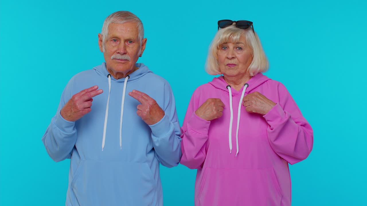 Smiling Elderly Couple Pointing Fingers