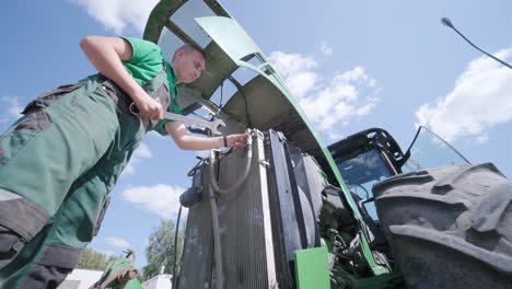 farmer mechanic repairing tractor. open tractor hood, engine. repair agricultural technology