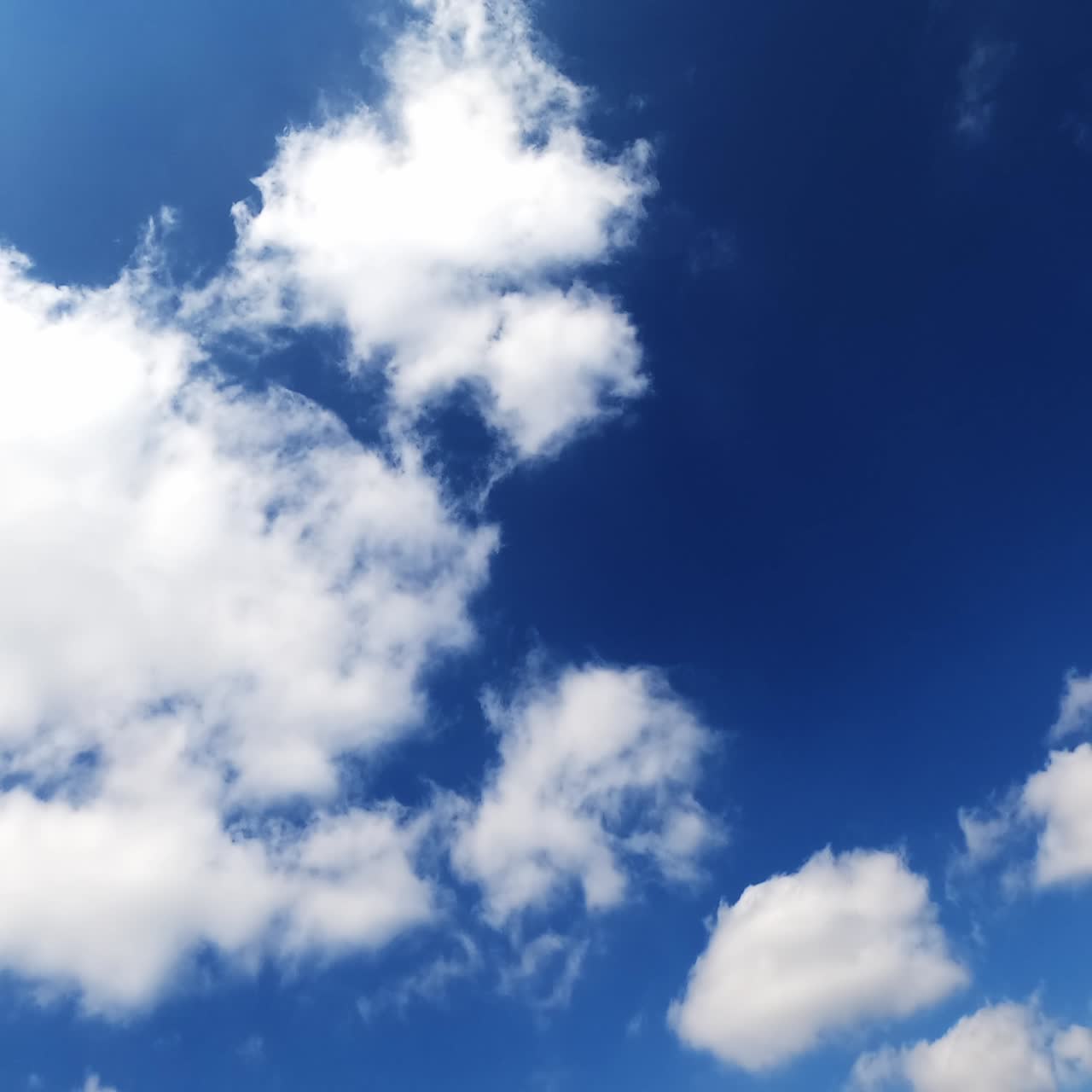 White cotton clouds floating fast in the sky. Blue summer sky with beautiful clouds. Time lapse