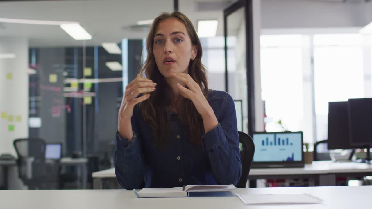 mujer de negocios caucásica sentada en un escritorio haciendo una videollamada gestando
