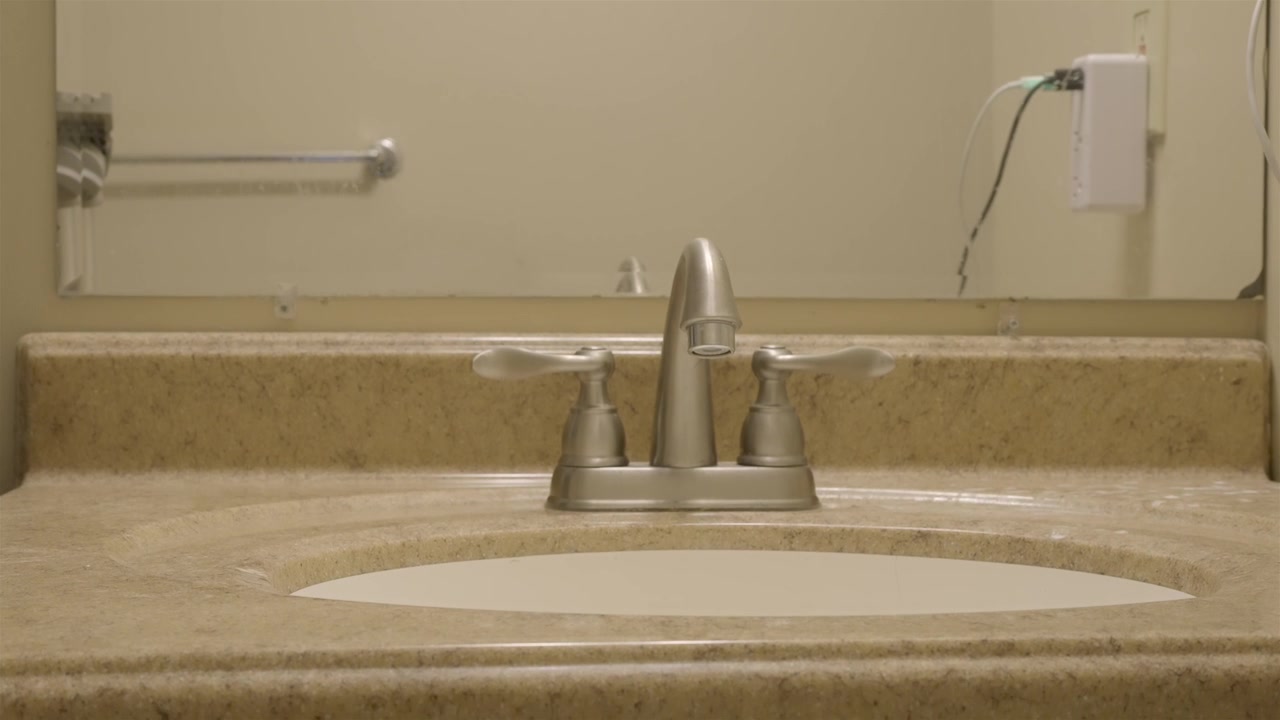Un propriétaire répare le système de drainage de sa salle de bain, effectuant un dépannage par le dessous.