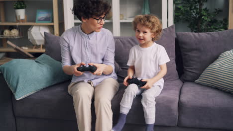 mother and son playing video games together on a couch