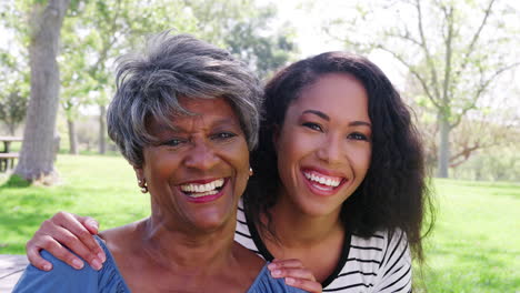 portrait of senior mother with adult daughter relaxing in park