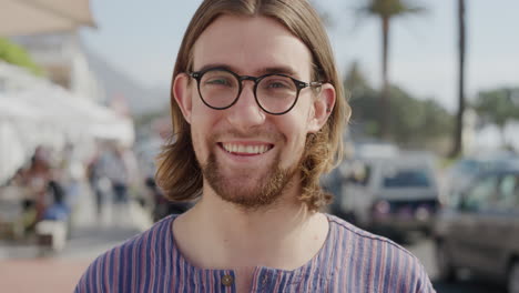 Porträt-Eines-Netten-Jungen-Nerd-Mannes-Mit-Brille,-Der-Lächelt-Und-Die-Sonnigen-Sommerferien-Im-Freien-Genießt-Und-Ruhig-Auf-Einer-Belebten-Städtischen-Strandreihe-Mit-Echten-Menschen-Aussieht