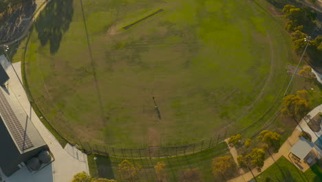 aerial perspective of people kicking australian football at empty oval