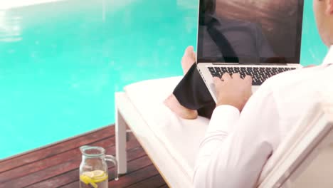 Businessman-using-laptop-while-lying-on-deckchair