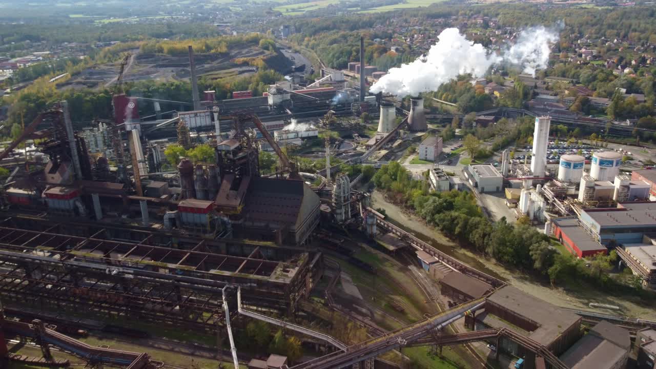 Trinec industrial district showing factory and smokestacks, Czech Republic, high angle aerial pullback over chutes and tubes above train tracks