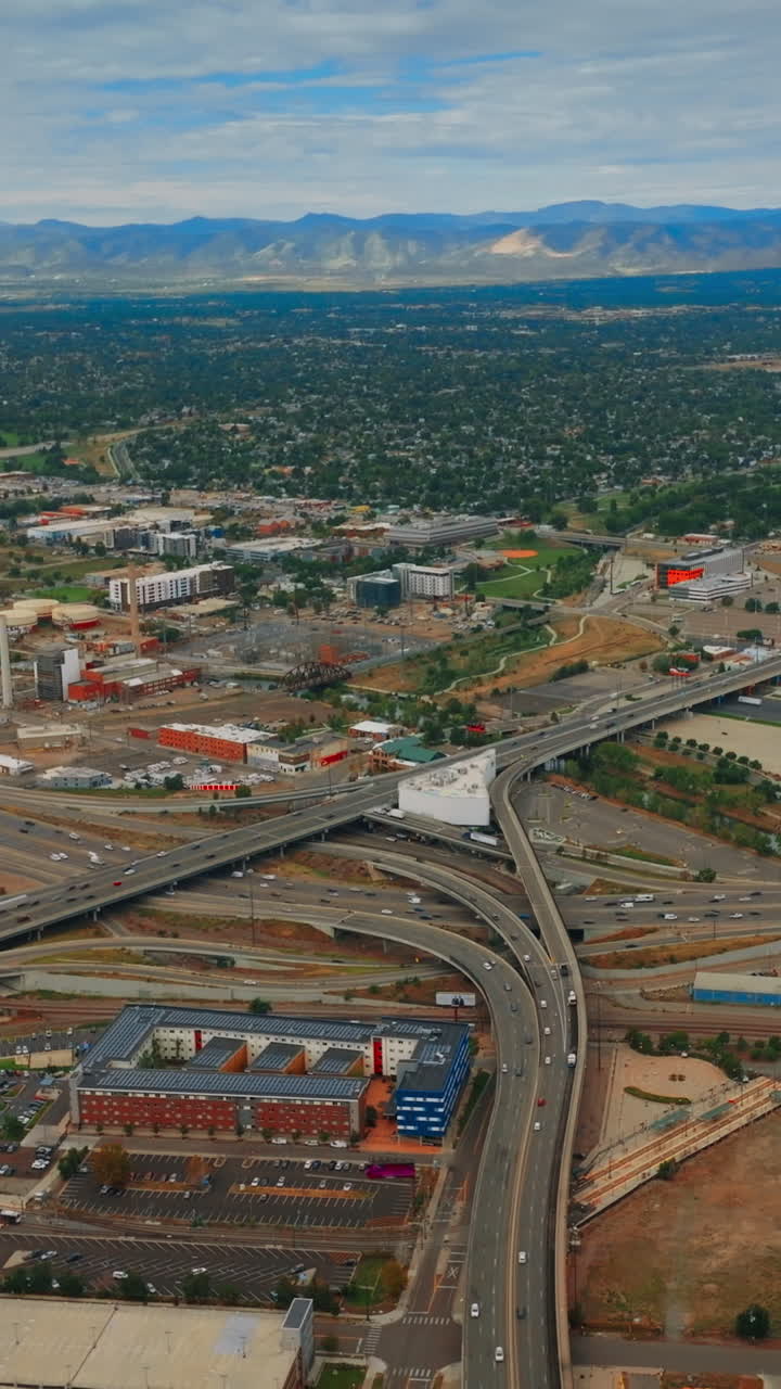 Tangled system of roads crossing Denver, USA. Lively road traffic of metropolis at daytime. Colorado mountains at backdrop. Vertical video
