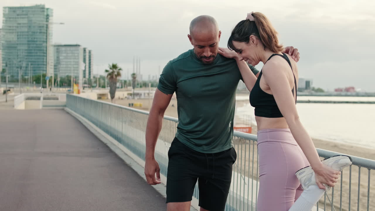 Casal feliz alongando as pernas em um calçadão de praia urbana