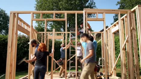 a group of people works together to construct a wooden frame structure in a backyard. the sun shines bright as they collaborate and use tools safely, showcasing teamwork and effort.