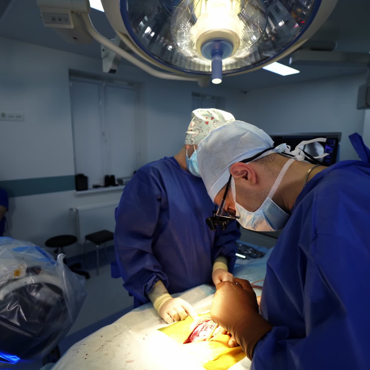 Modern operating theatre. Professional neurosurgeon and female assistant in medical uniform conduct a surgery on a patient's body. Health care concept