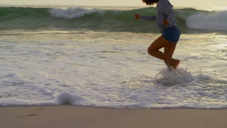 Low-section-of-woman-playing-with-sea-waves-on-the-beach-4k