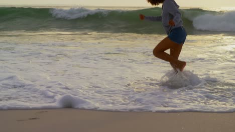 sección baja de la mujer jugando con las olas del mar en la playa 4k