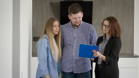 retrato de marido y esposa consultando con un agente inmobiliario femenino en el interior