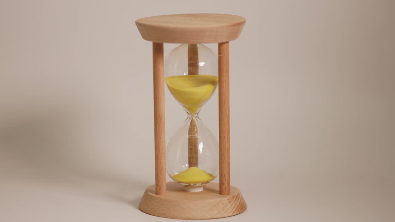 Yellow sand falls in an hourglass timer.