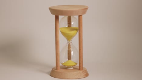 yellow sand falls in an hourglass timer.